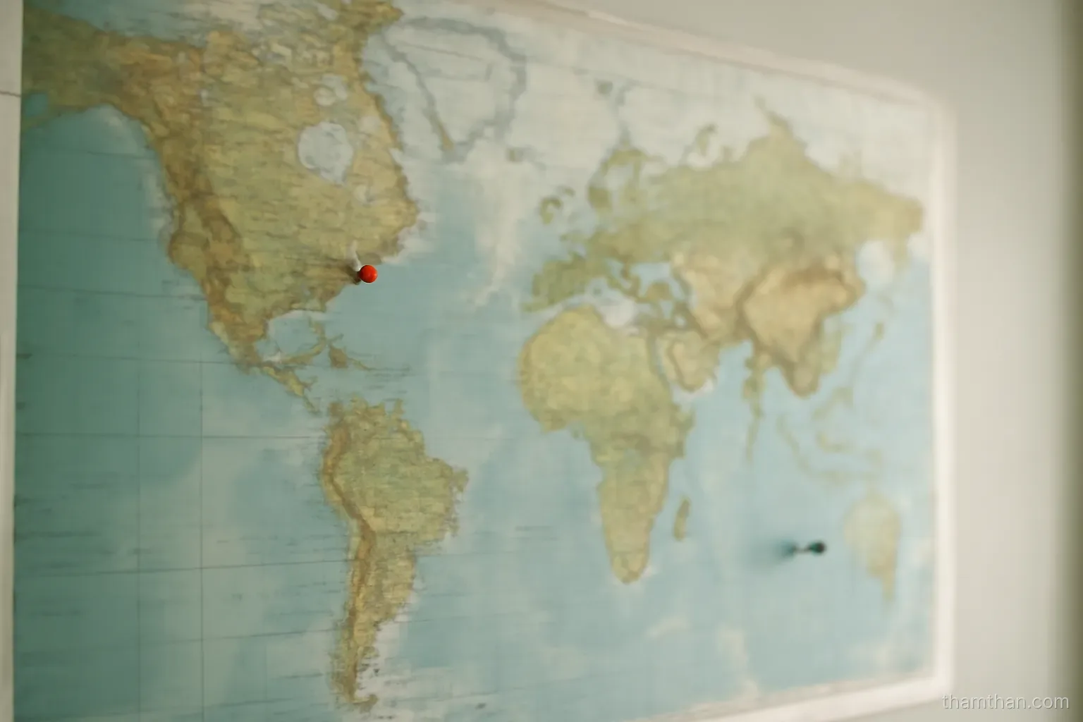 a world map on a wall with two small pins placed far apart on it